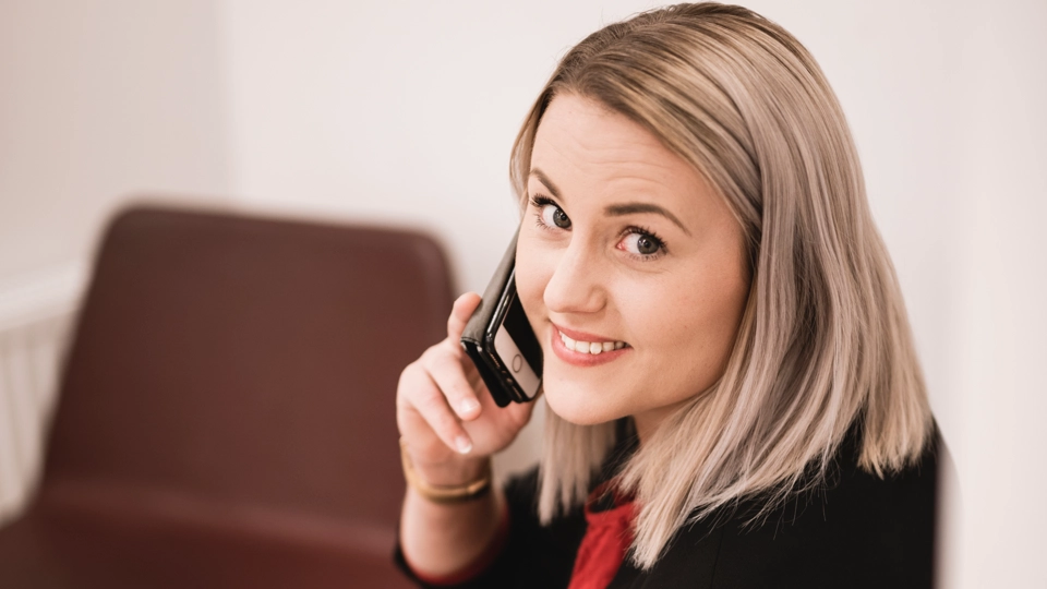 En kvinna som sitter på en stol och pratar i mobiltelefonen.