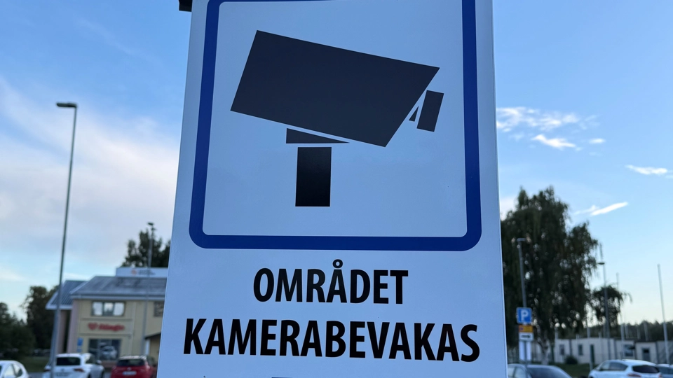 En vit skylt med en kameraikon och information om att området kamerabevakas.