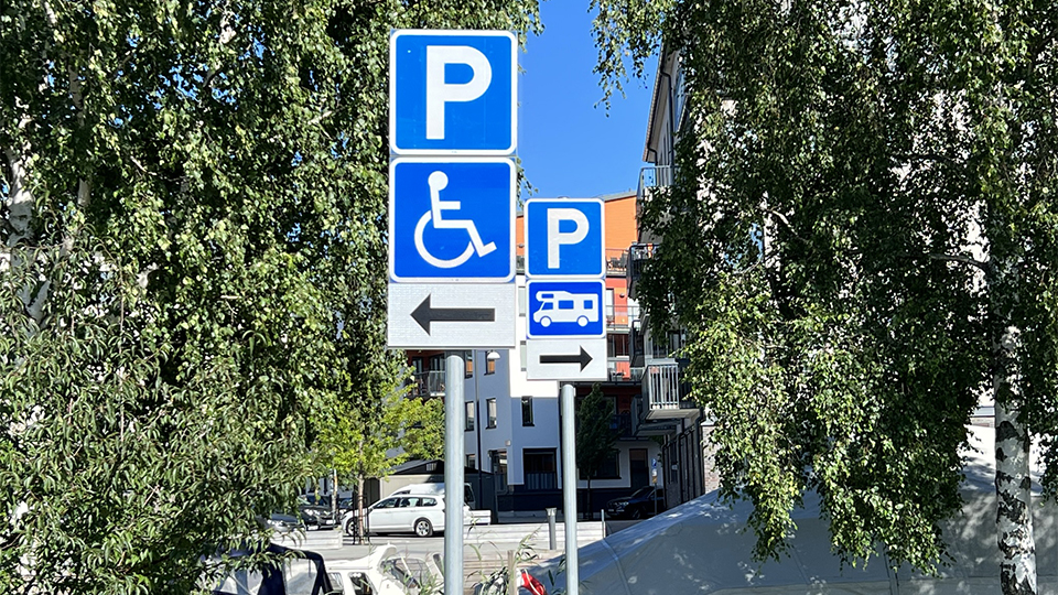 Två skyltar. Den ena visar symbol för parkering för funktionshindrade, den andra en symbol för husbil.