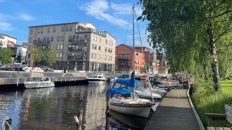 Östra Kanalstaden i centrala Åkersberga. Åkers kanal i förgrunden med flerfamiljshus och bryggor med förtöjda båtar.