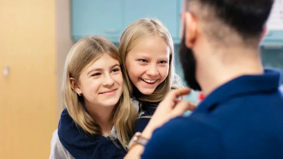 Barn ler och kramas, pedagog pratar med barnen