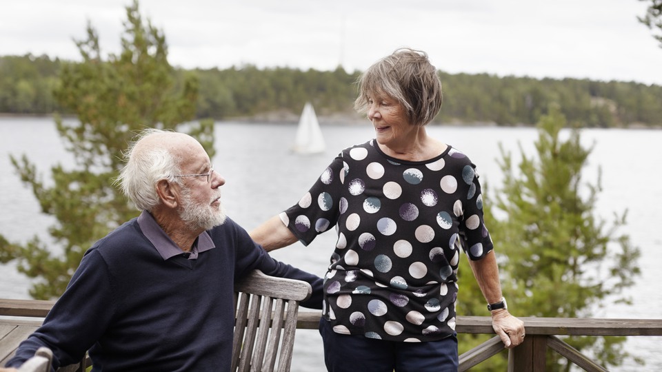 Äldre par tittar på varandra, i bakgrunden seglar en båt på vatten