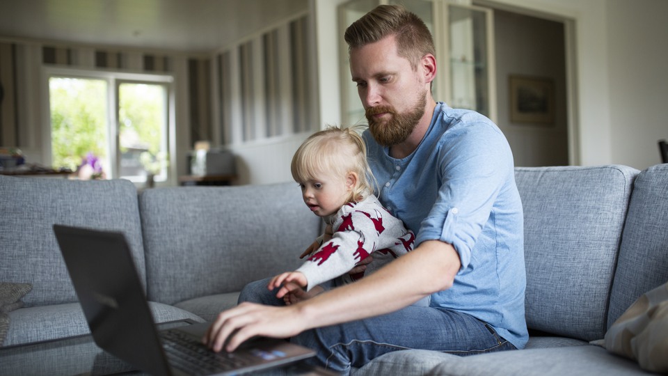 Förälder och barn sitter i en grå soffa. Skriver på datorn 