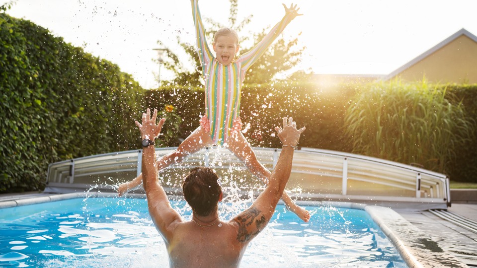 En pappa badar i poolen med sin dotter.