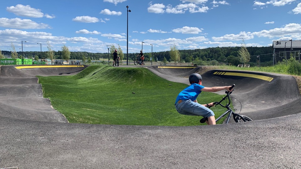 En ung person cyklar i en böljande svart bana. Det ser ut att gå fort!