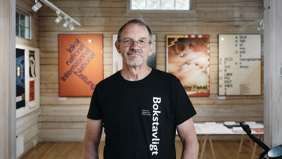 Personporträtt på Örjan Nordling i Konsthallen på Länsmansgården. Han har en svart t-shirt som det står Bokstavligt på i vit text.