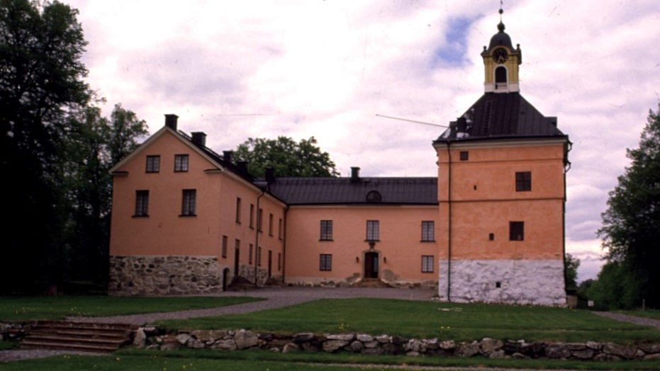 Ett slott sett framifrån. Det är putsat i ljust aprikosfärg.