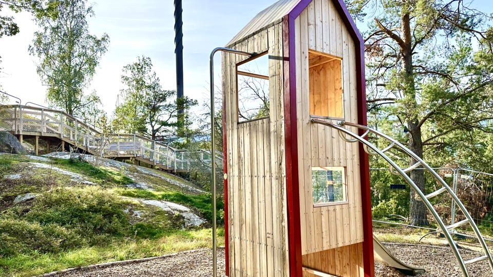 Bild på ett trähus på ett berg med stege och rutschkana - påminner lite om en fågelholk