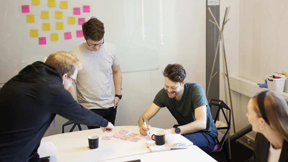 Två personer sitter och skrattar vid ett skrivbord.