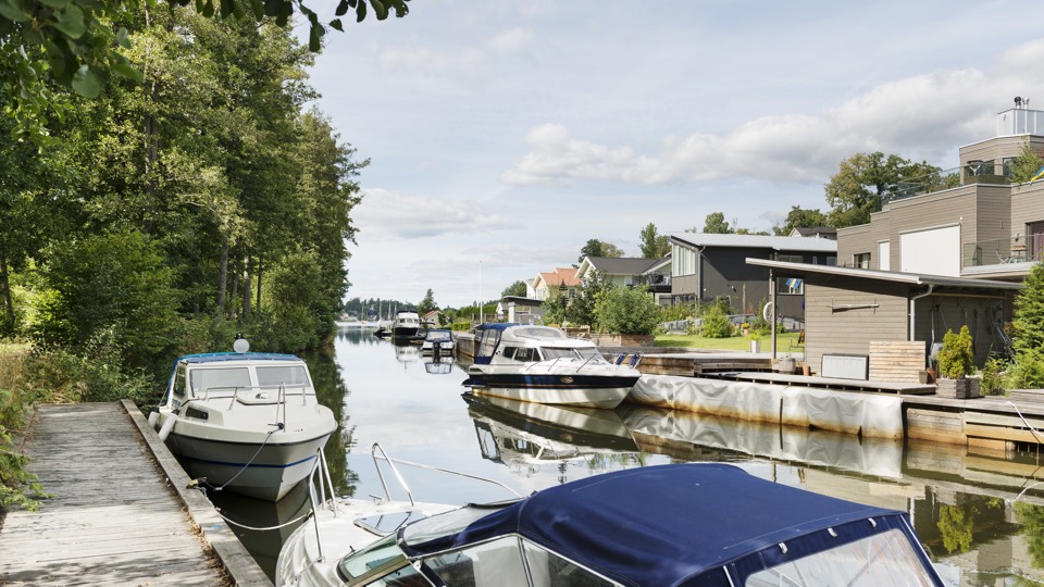 Bilden föreställer några hus vid en kanal med några förtöjda båtar.
