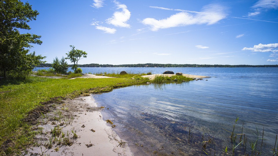 En havsvik med sandstrand en solig sommardag.