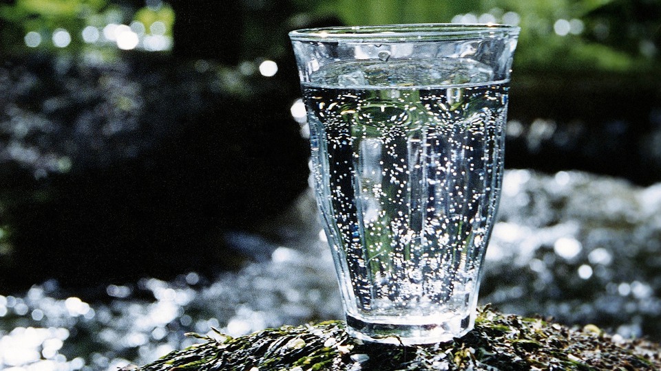 Glas med vatten som står på en sten i naturen.