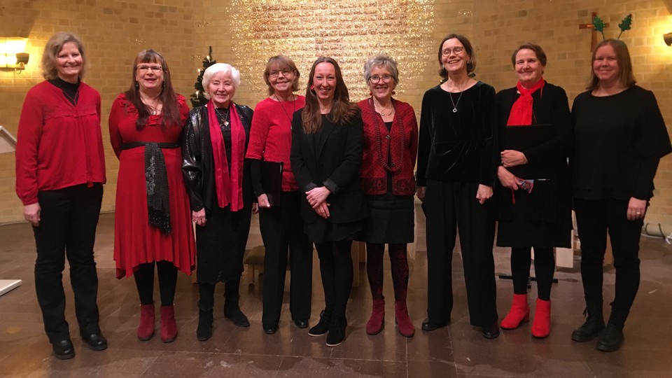 Ryhmä naisia yheiskuvassa punaisissa ja mustissa vaatteissa. 