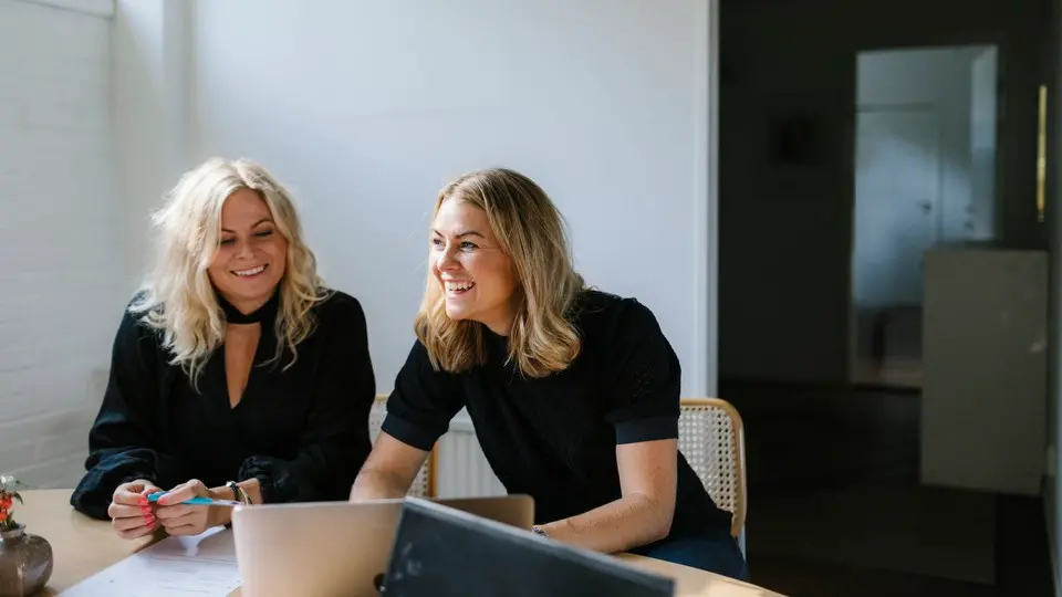 Två glada personer sitter vid ett skrivbord