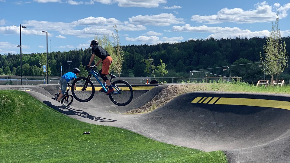 Två unga personer åker på cyklar i en pumptrackbana.