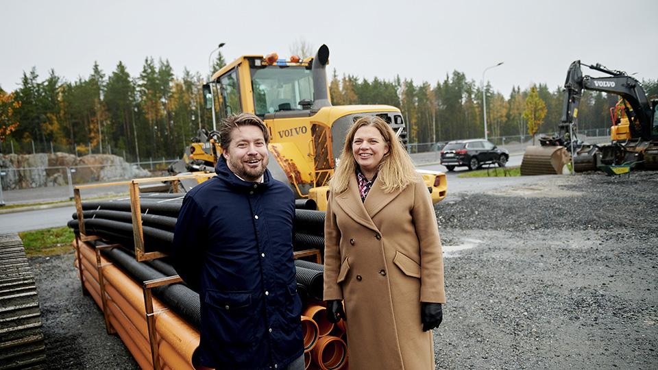 Fredrik Nestor, chef för mark och stora projekt i Österåkers kommun, och Kristina Eineborg, utvecklings- och näringslivsdirektör i Österåkers kommun, står framför en grävskopa på området Brännbacken.