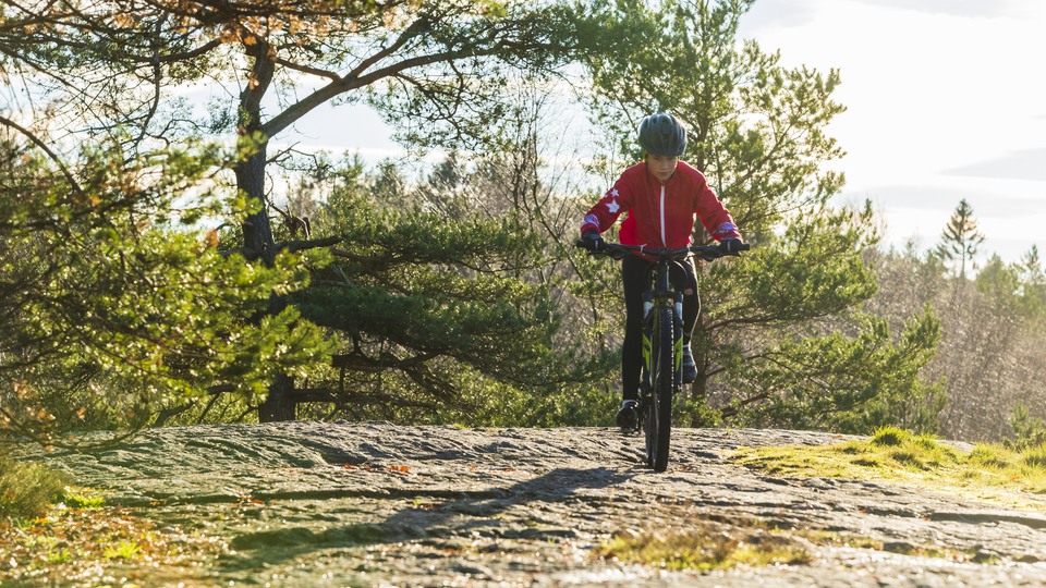 Barn som cyklar mountainbike nedför en berghäll. 