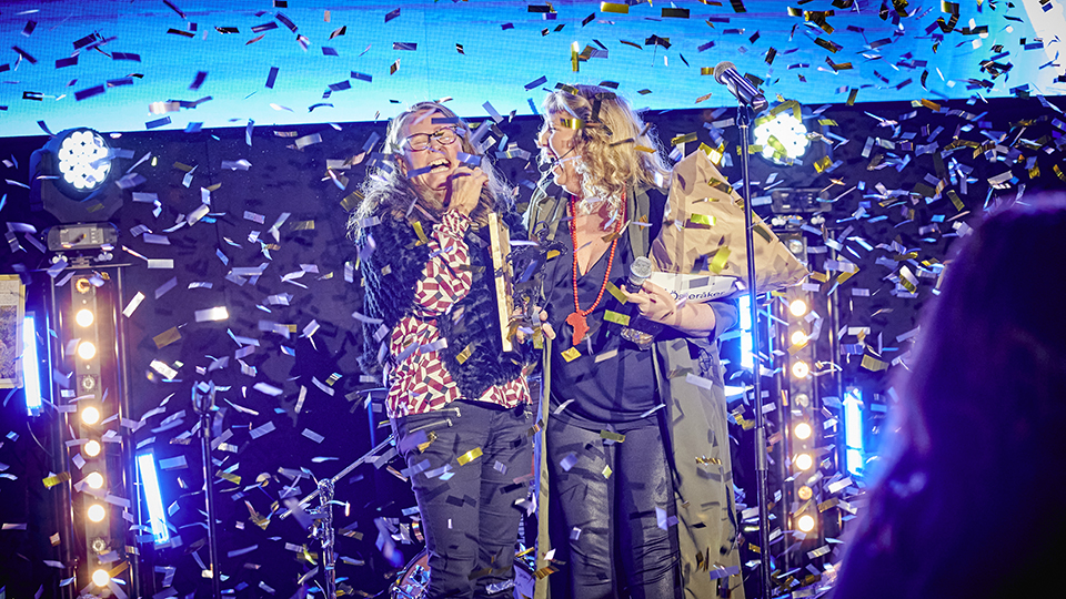 Årets möjliggörare Karin Olofsson står i ett regn av konfetti och ler tillsammans med konfenercier Frida Samuelsson