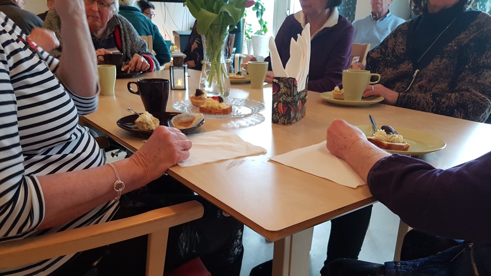Äldre personer samlade till samkväm runt ett bord
