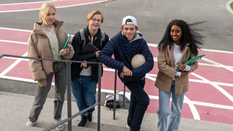 Fyra ungdomar står bredvid varandra på en skolgård.