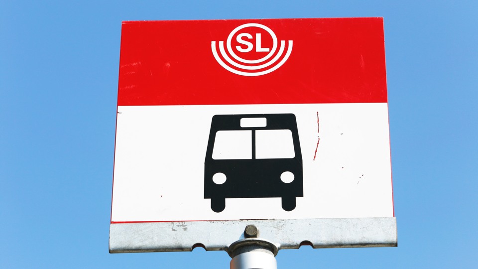 En skylt på en busshållplats mot en blå himmel.
