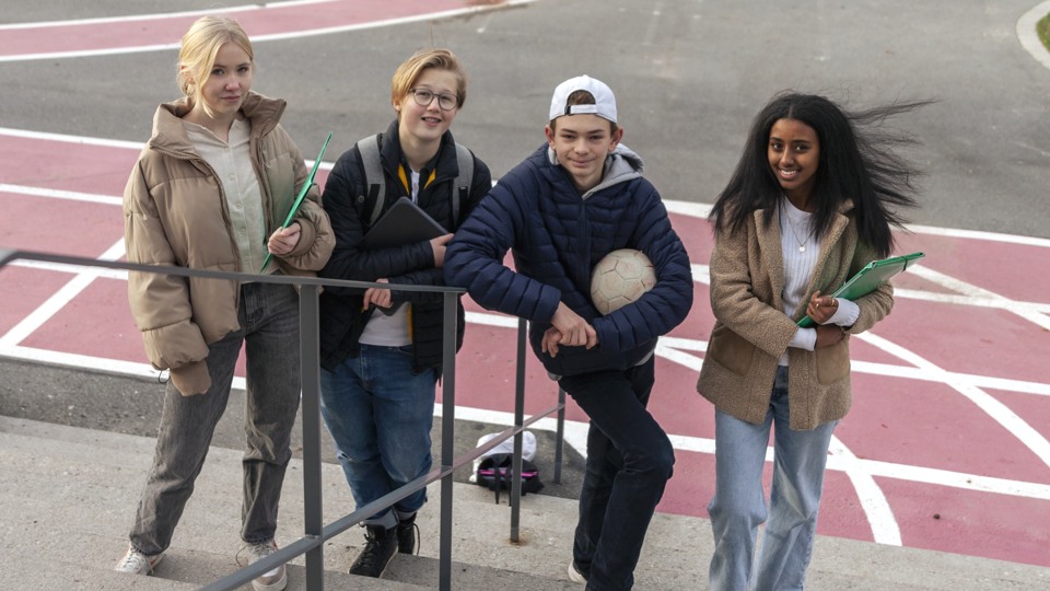 Fyra ungdomar står på en skolgård