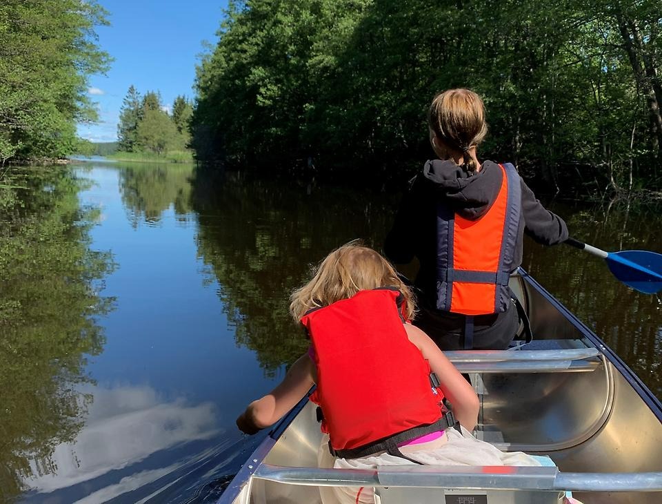 Kuva kaksi henkilöä kanootissa veden ympäröimänä
