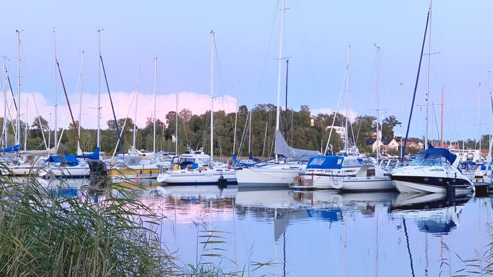 Hamn i kvällsljus med ett flertal båtar vid kajen. 