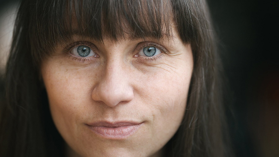 Närbild på en kvinna med blå ögon och mörk page med lugg,