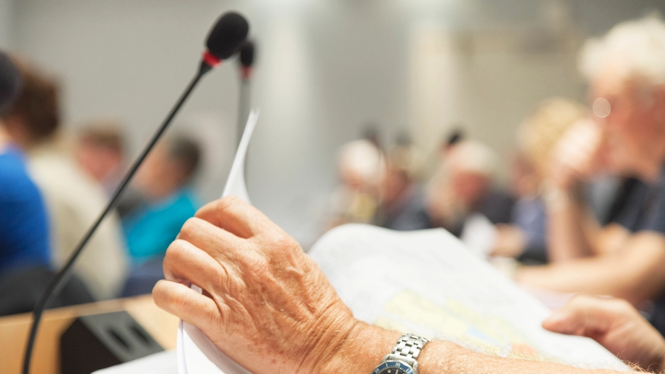 En person som håller ett papper framför en mikrofon.