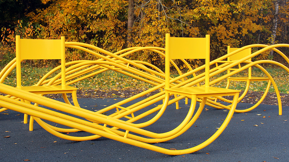 Tre stolar med förlängda, böjda ben. De ser ut som uttänjda gungstolar som sitter ihop med varandra.