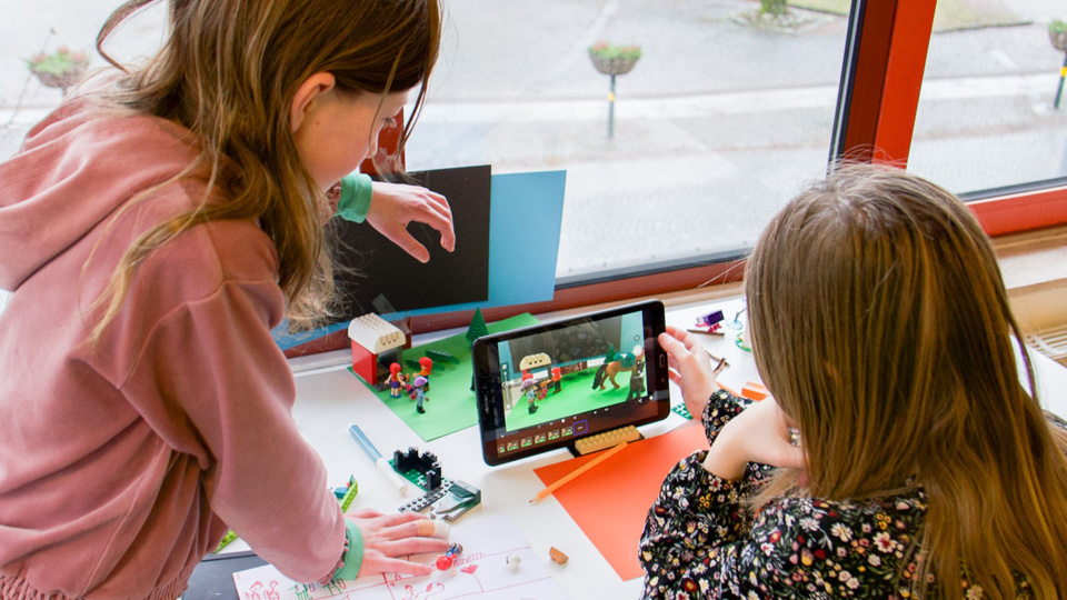 Två barn tittar på en padda med avfilmade ledsaksfigurer.