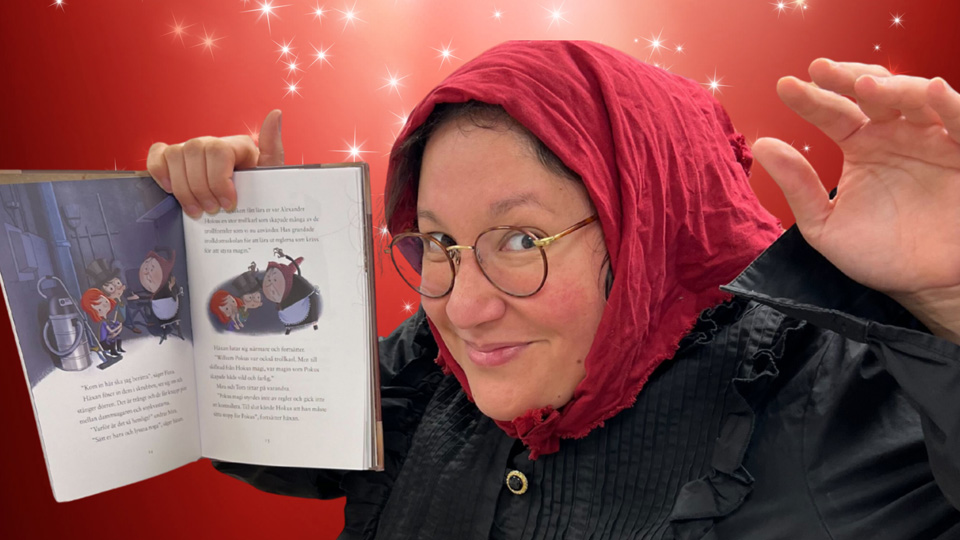 En glad kvinna i huckle håller upp en sagobok.