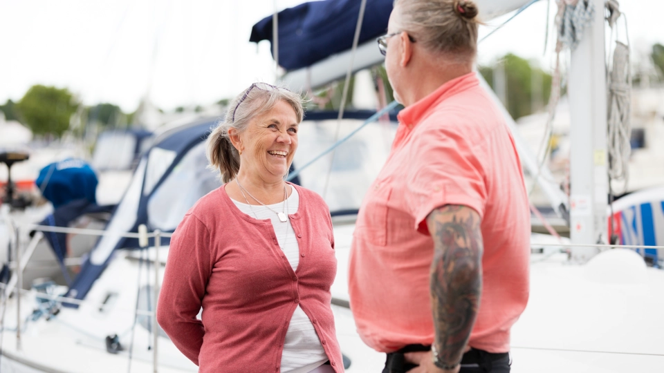 Två lite äldre personer, en man och en kvinna, står på en båtbrygga en sommardag.
