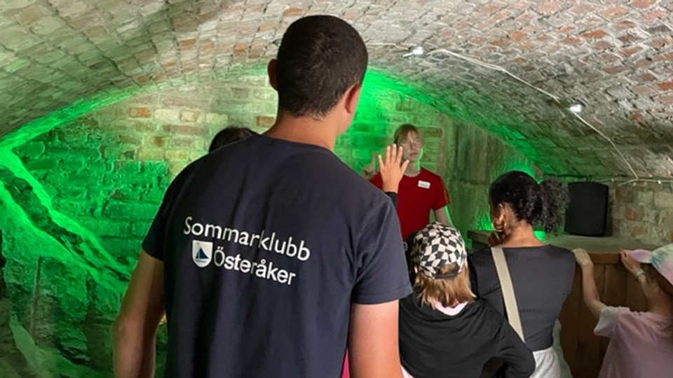 En ung person sedd bakifrån med en tröja som det står Sommarklubb Österåker på besök i Vaxholms fästning.