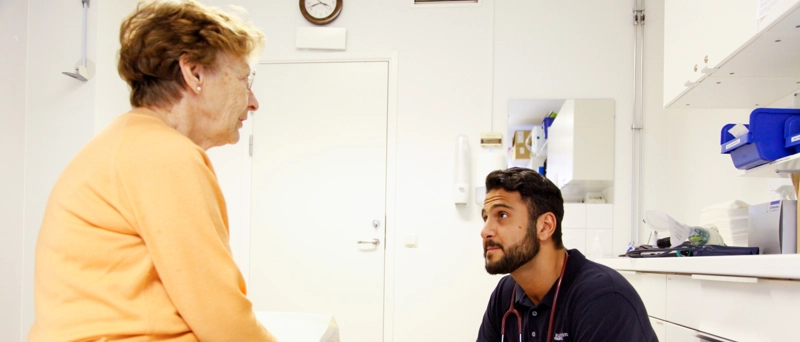 Mieslääkäräri istuu vastapäätä naista joka on tullut vastaanotolle.