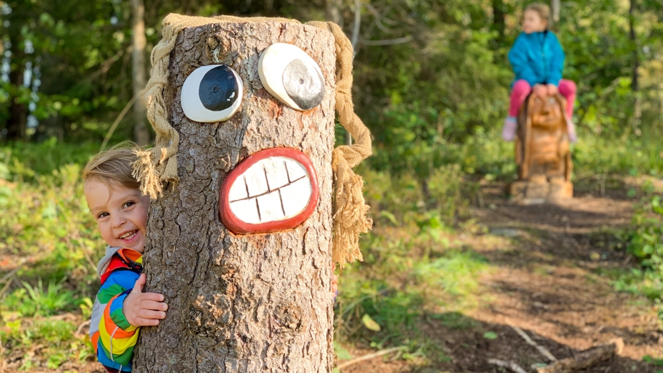 En pojke står i Trollskogen bakom ett av trollen.