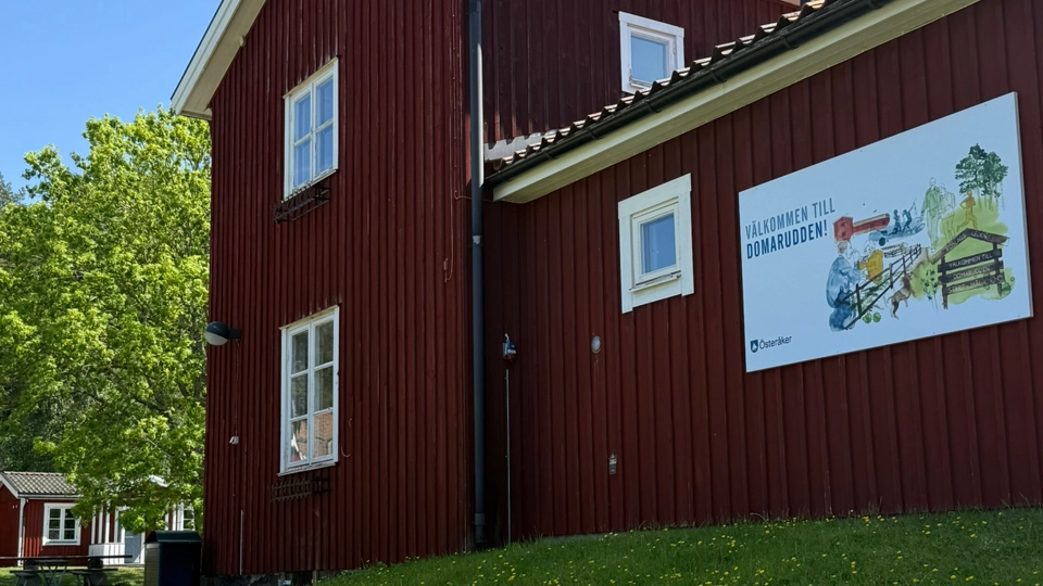 En faluröd byggnad med en skylt som det står Välkommen till Domarudden på.
