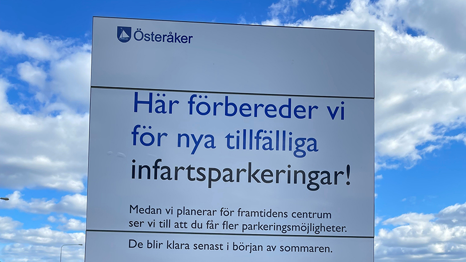En vit skylt med Österåkers kommuns logga och texten Här förbereder vi för nya tillfälliga infartsparkeringar