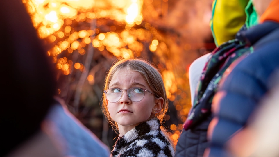 En ung flicka framför en valborgsbrasa.