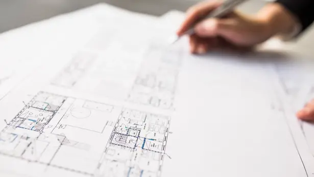 Hus under utbyggnad, person arbetar i förgrunden