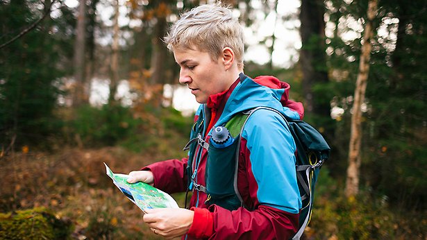 Person i en skog läser en karta