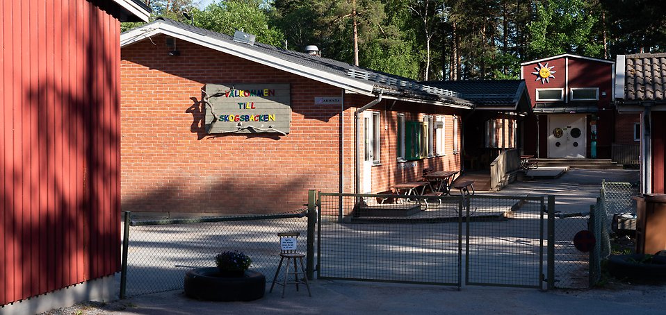 Skogsbackens förskola, byggnad i trä och tegel. På gården finns bänkar och sandlåda