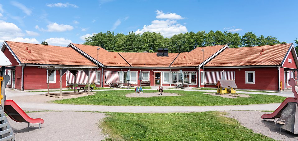 Säby förskola, röd träbyggnad med gräsplan och lekställningar framför