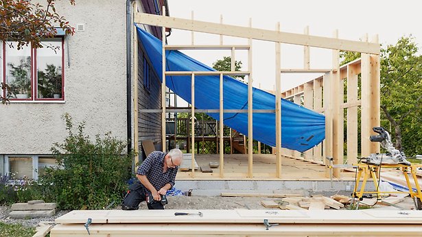 Hus under utbyggnad, person arbetar i förgrunden