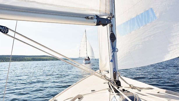 Bild från en segelbåtsmast med en annan segelbåt ute på havet i förgrunden.