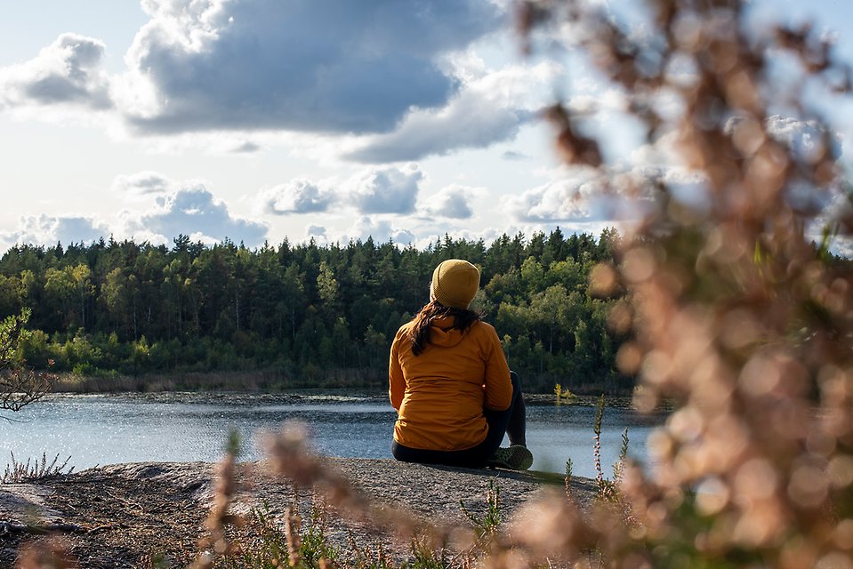 Kvinna sitter på klippa vid havet