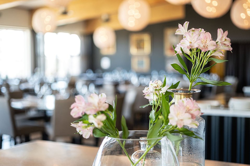 En bukett med skira blommor på ett restaurangbord.