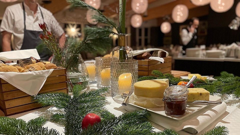 Bild på ost och bröd framdukat i restaurangmiljö med omgivande julpynt