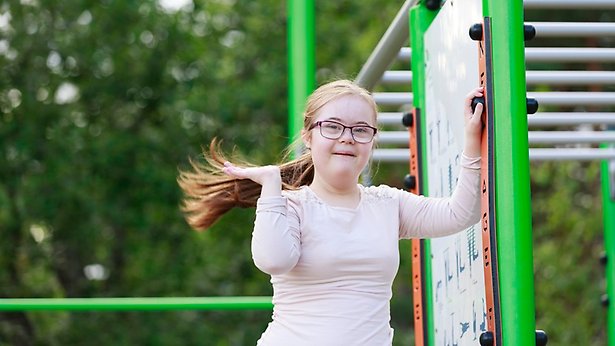 Fyra personer går i en park. En av dem är rullstolsburen.